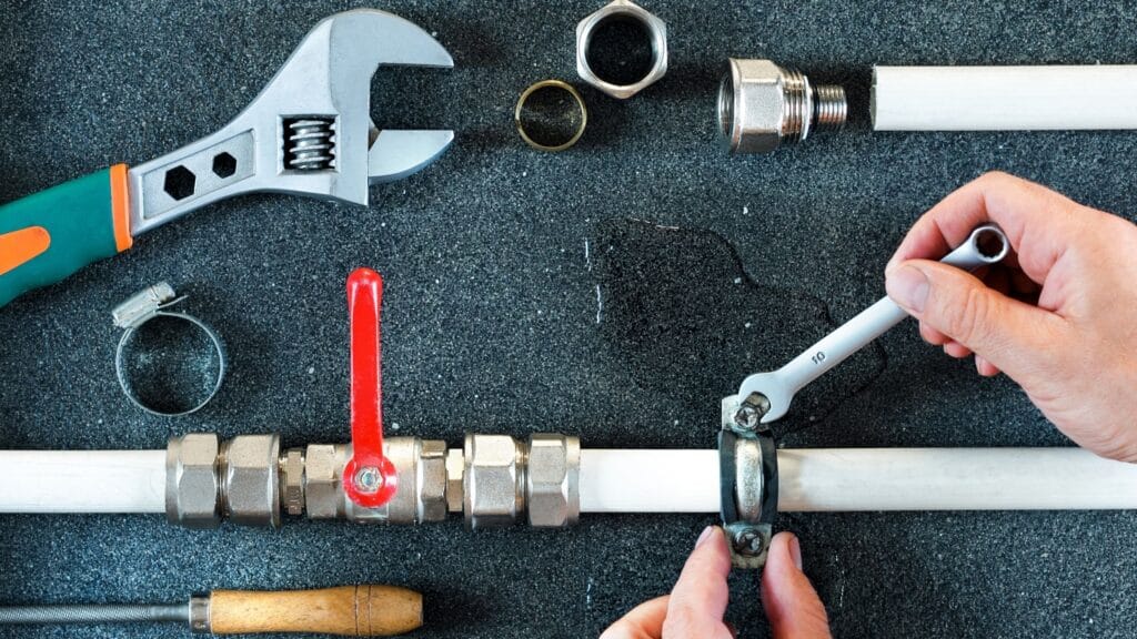 Plumber repairing a pipe valve with an adjustable wrench in Chandler