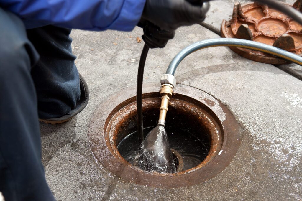 Plumber hydro jetting a sewer line through a manhole in Chandler