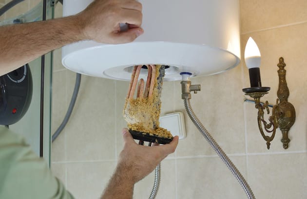 Technician removing mineral buildup from a water heater in Chandler