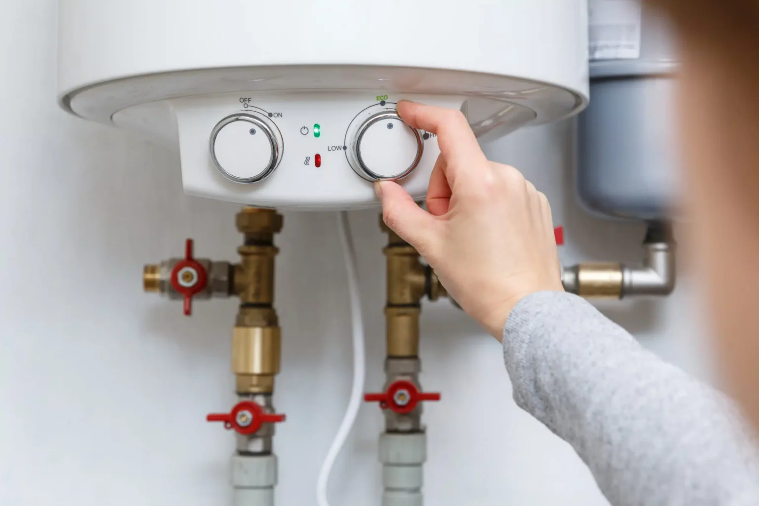 Homeowner adjusting the temperature controls on a water heater in Chandler